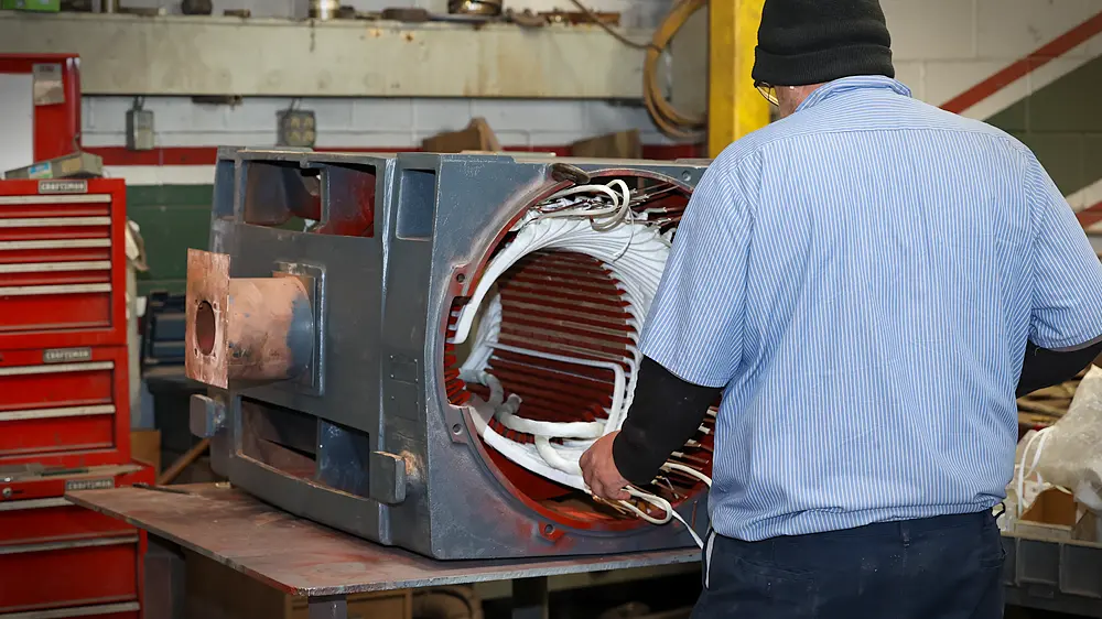 Technician Rewinding electric motor with copper wire.