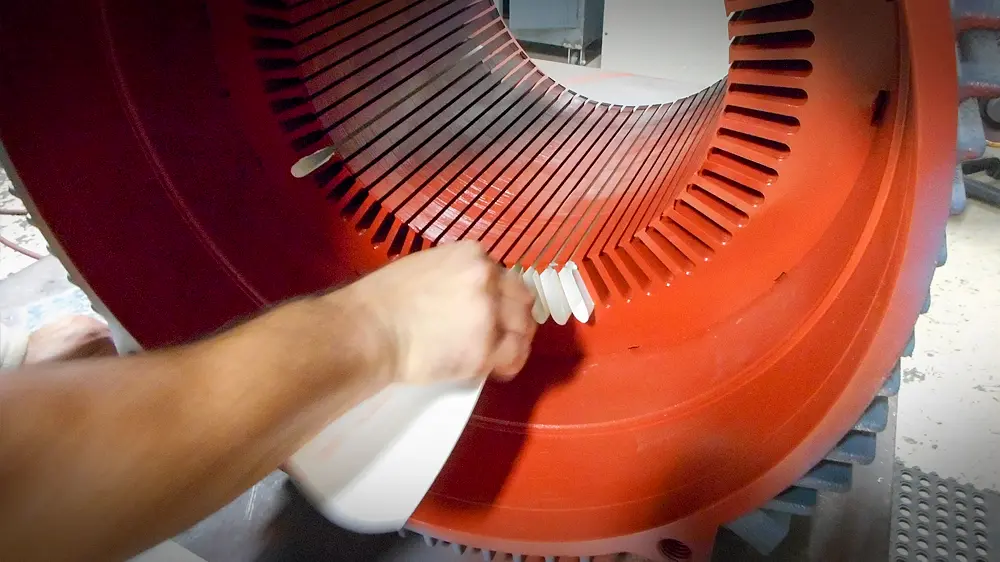 Installing new insulation paper lining into the stator slots.