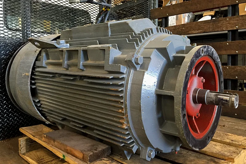 Large electric motor on pallet at Electric Motor Shop, photographed on arrival to document condition and components before repair.