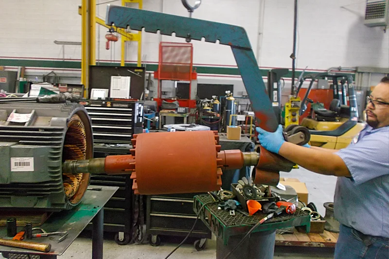Rotor being extracted from motor housing with lifting tool during detailed disassembly process.