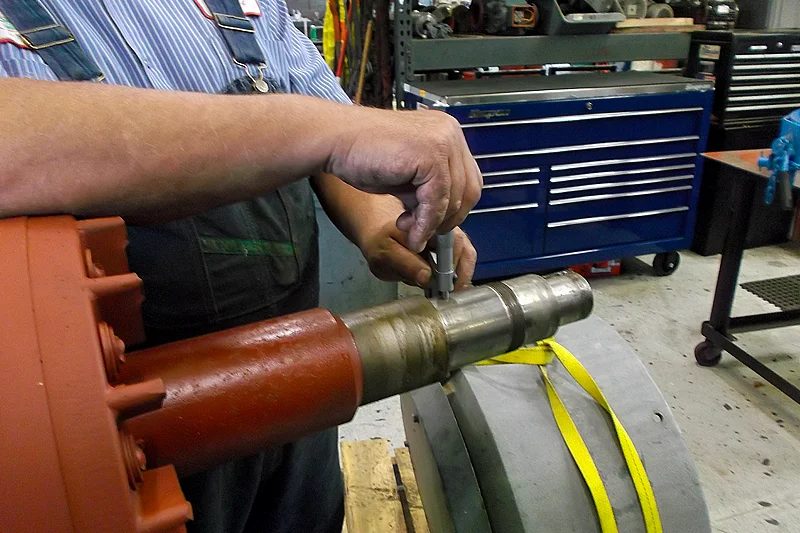 Technician measuring rotor shaft diameter with micrometer to ensure precise machine fit.
