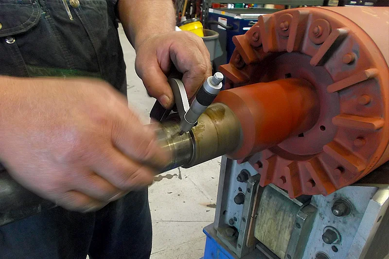 Detailed view of micrometer used to inspect shaft dimensions on electric motor rotor.
