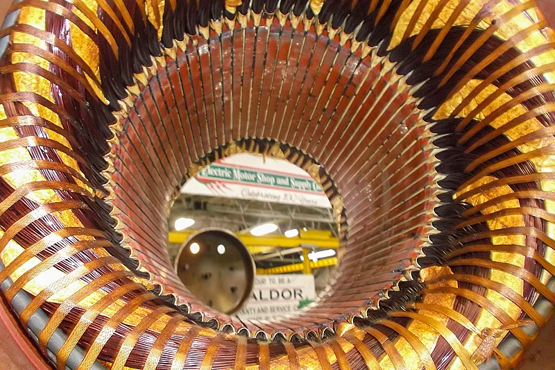 Interior view of electric motor stator showing copper windings during visual inspection for electrical failure.