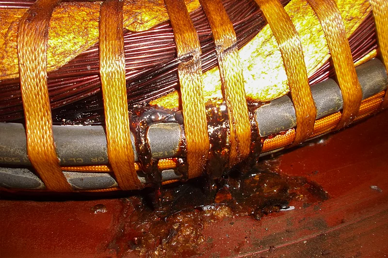 Severely contaminated and burnt stator winding with signs of insulation breakdown and motor failure.