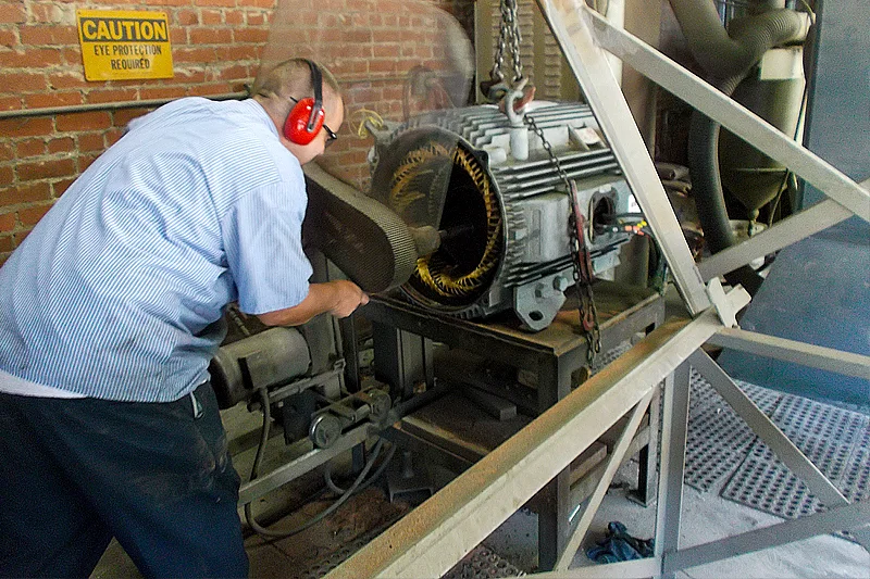 Technician at Electric Motor Shop preparing stator for burnout process to remove old windings safely.