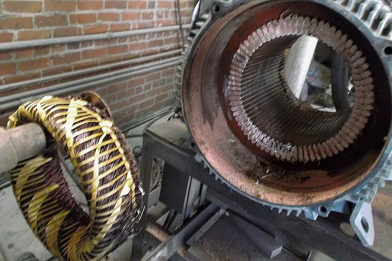Stator with damaged windings partially extracted, prepped for complete removal and rewind.