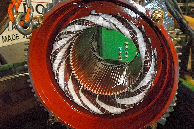 Close-up view of a stator with newly wound coils fully wrapped in white insulation, ready for resin impregnation. The interior is clean and precisely organized.