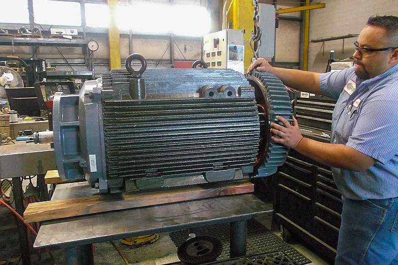 Technician guiding the end bell into position as part of the final motor assembly process.
